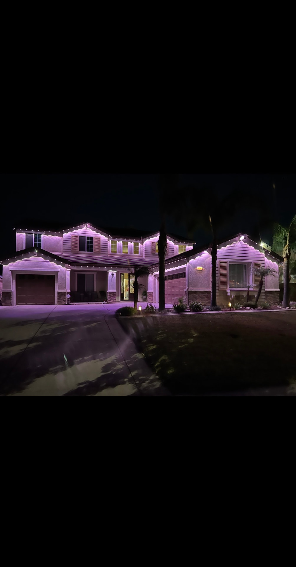 Large home glowing pink and purple with permanent LED lighting